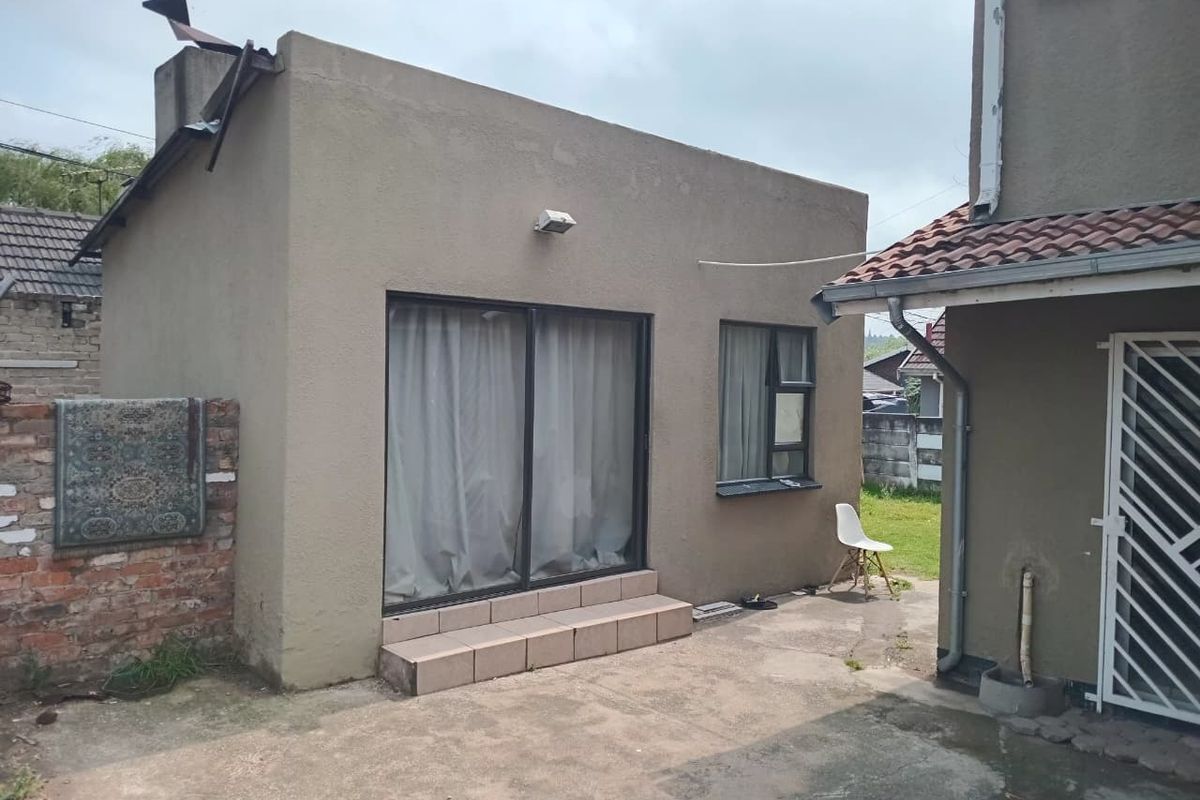 Rear exterior view of the property featuring a concrete patio, sliding glass door access, and a brick boundary wall.