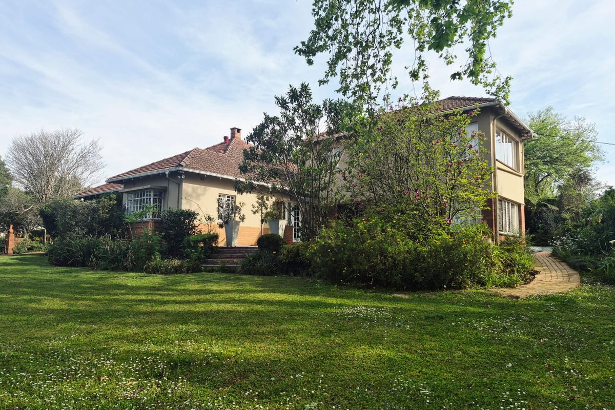 A view of the rear elevation of the house, featuring a well-maintained garden, paved pathways, and traditional brick and tile construction.