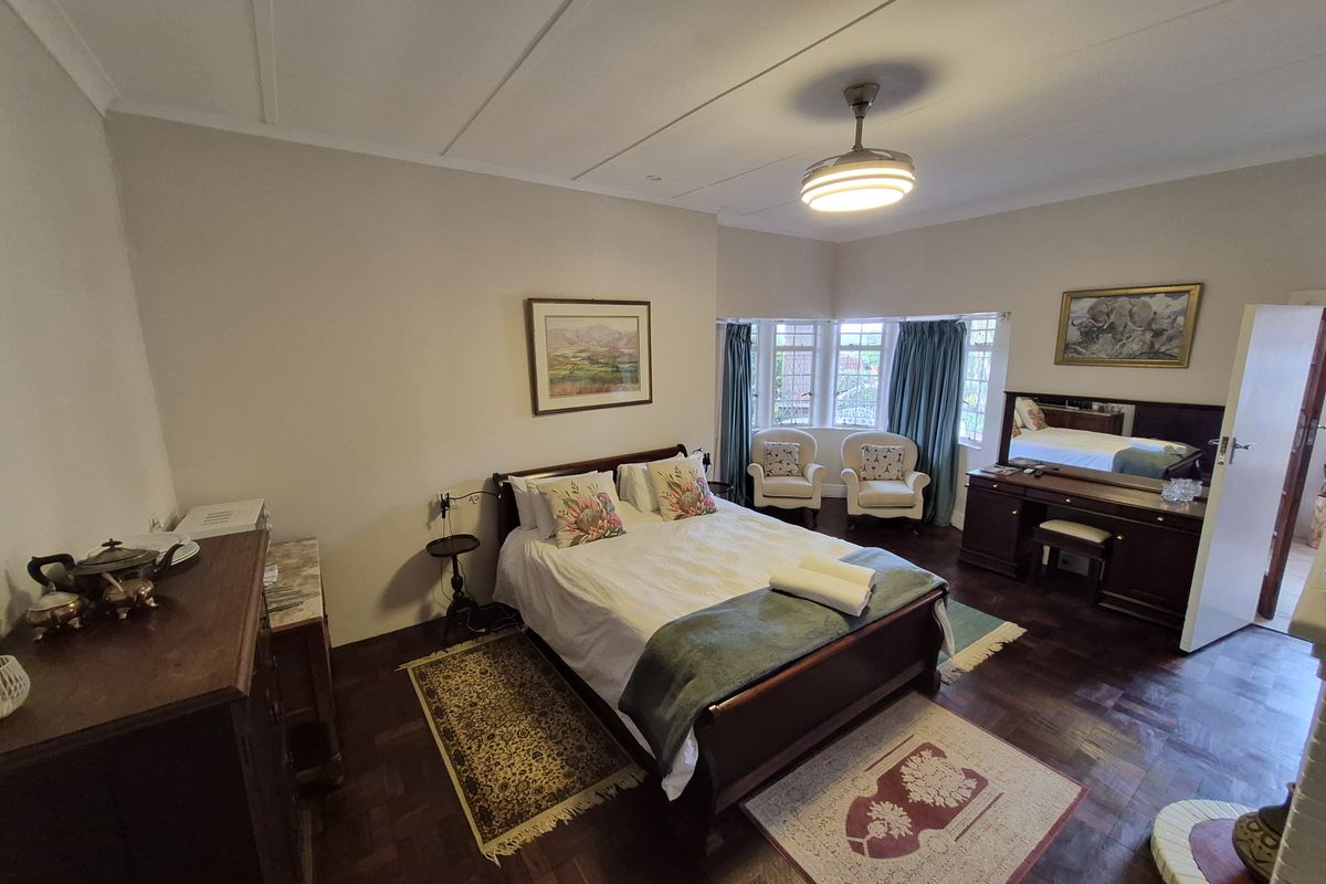 Spacious bedroom featuring classic parquet flooring, a ceiling fan, and a charming bay window that allows for natural light.
