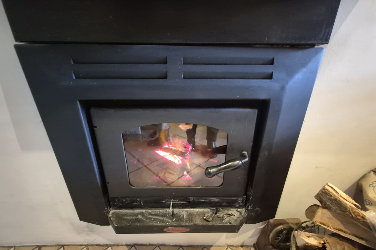 A close-up view of a built-in fireplace with a glass door and active fire, set against tiled flooring.