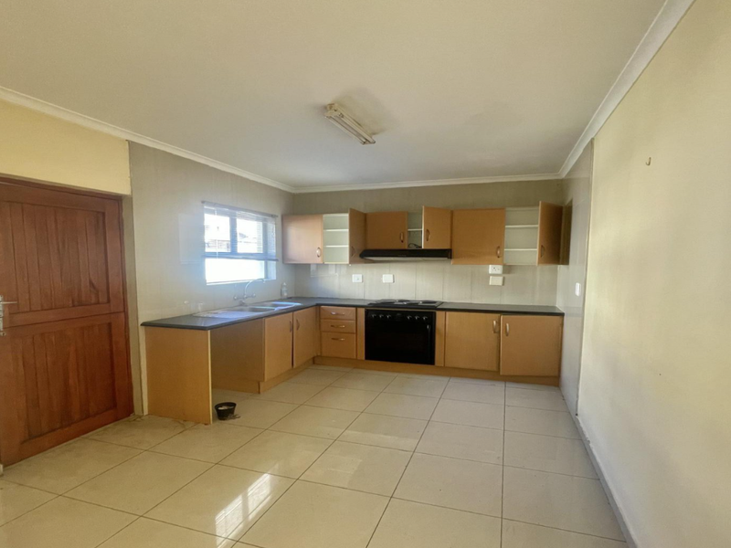 A functional kitchen featuring built-in cabinetry, a built-in oven with extractor fan, and tiled flooring, offering a blank canvas for potential modern updates.