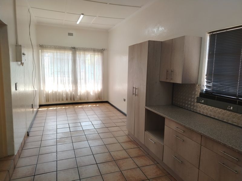 A functional kitchen area featuring built-in cabinetry, tiled flooring, and a metal splashback, offering a clean and practical space for culinary activities.