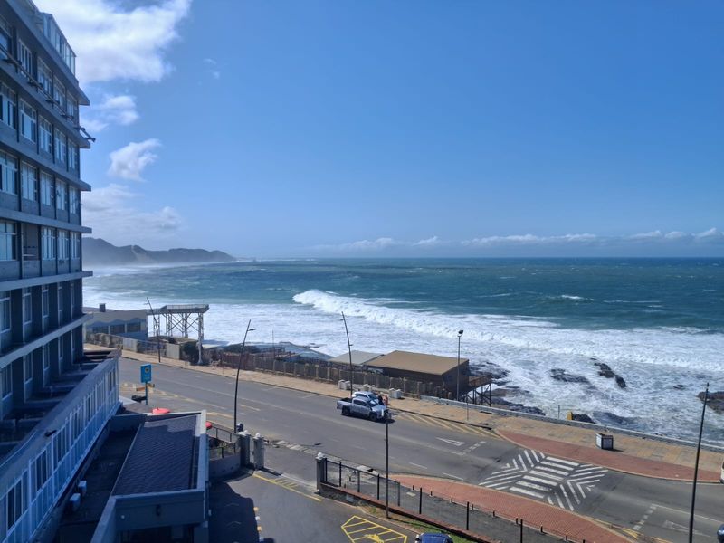 A scenic elevated view overlooking the coastline, ocean, and adjacent coastal road infrastructure.