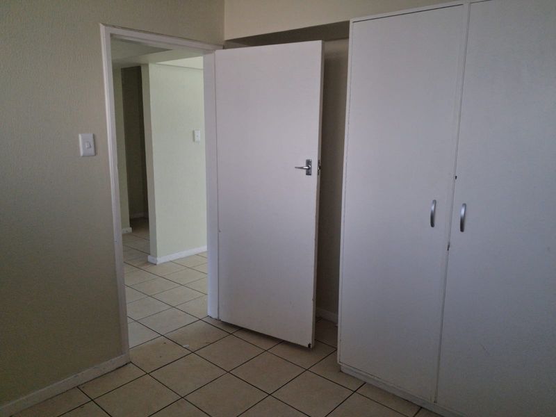 A vacant bedroom featuring tiled flooring and built-in cupboards, offering a neutral canvas for potential interior design updates.