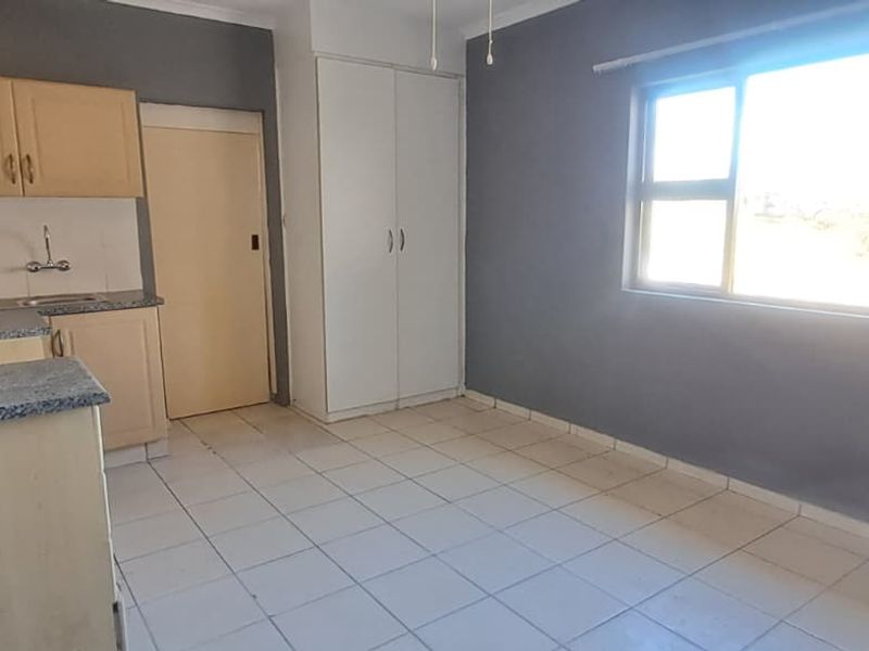A compact, empty kitchen featuring built-in cabinetry, laminate countertops, and tiled flooring, awaiting modernization to enhance its functionality and aesthetic appeal.