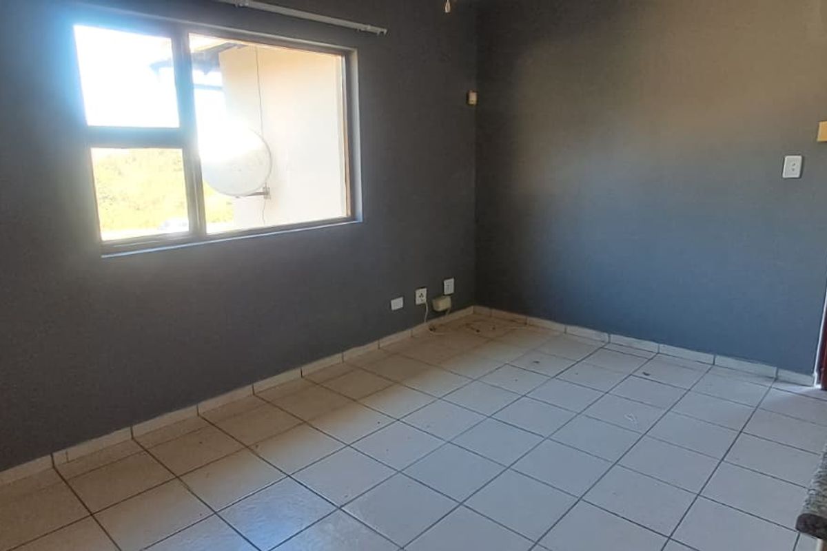 An empty living area featuring tiled flooring, dark grey walls, and a timber panel door, offering a blank canvas for interior design.