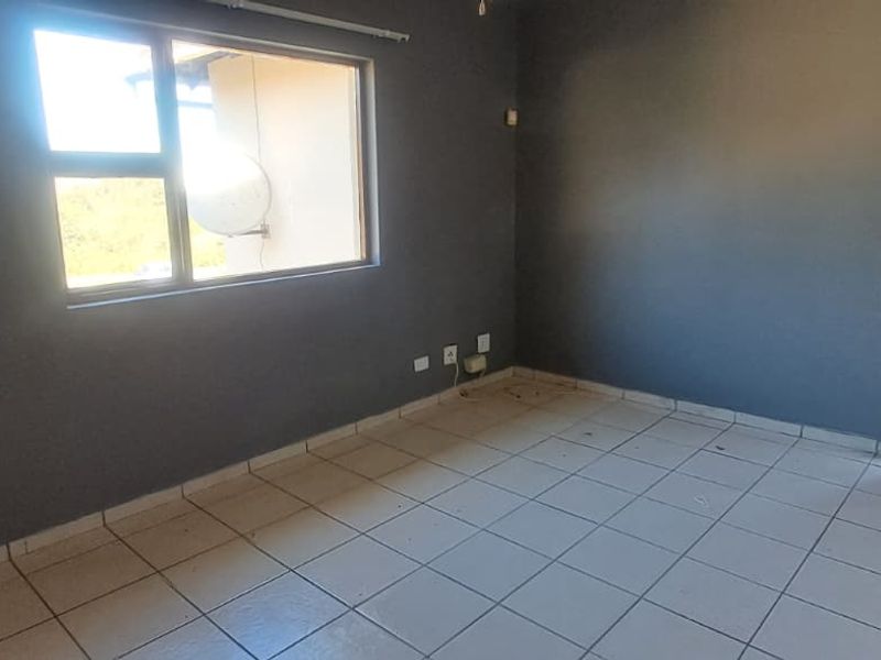 An empty living area featuring tiled flooring, dark grey walls, and a timber panel door, offering a blank canvas for interior design.