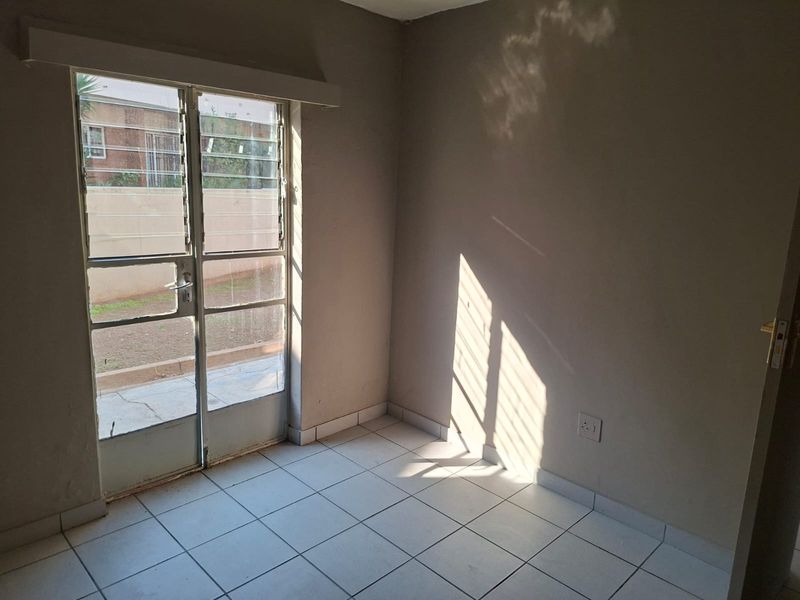 A vacant bedroom featuring tiled flooring and a glass door providing direct access to the exterior area.