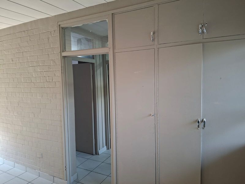 Bedroom featuring built-in cupboards, tiled flooring, and a painted brick wall, offering a blank canvas for renovation or interior design updates.