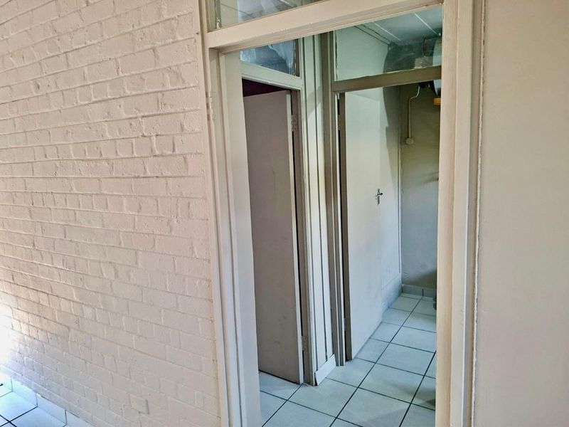 A functional hallway area featuring painted brick walls, tiled flooring, and multiple internal doorways with transom windows above.