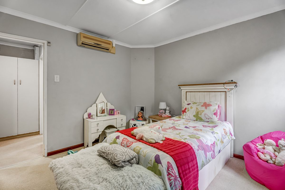 A functional bedroom featuring carpet flooring, a built-in wardrobe, and a wall-mounted split-system air conditioning unit.