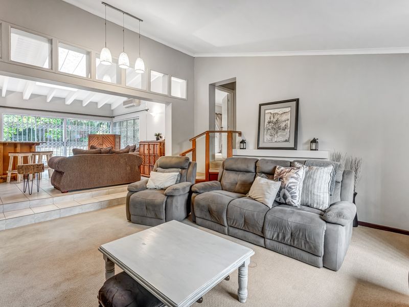 Spacious open-plan living area featuring a split-level design, exposed beam ceilings, and a staircase leading to upper levels.