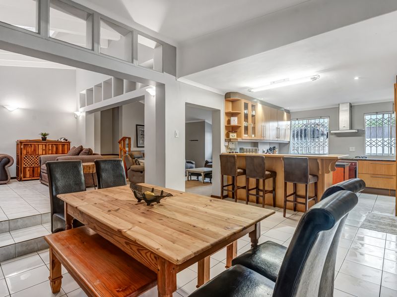 Spacious open-plan living and dining area featuring a functional kitchen with built-in cabinetry, an island breakfast bar, and tiled flooring throughout.