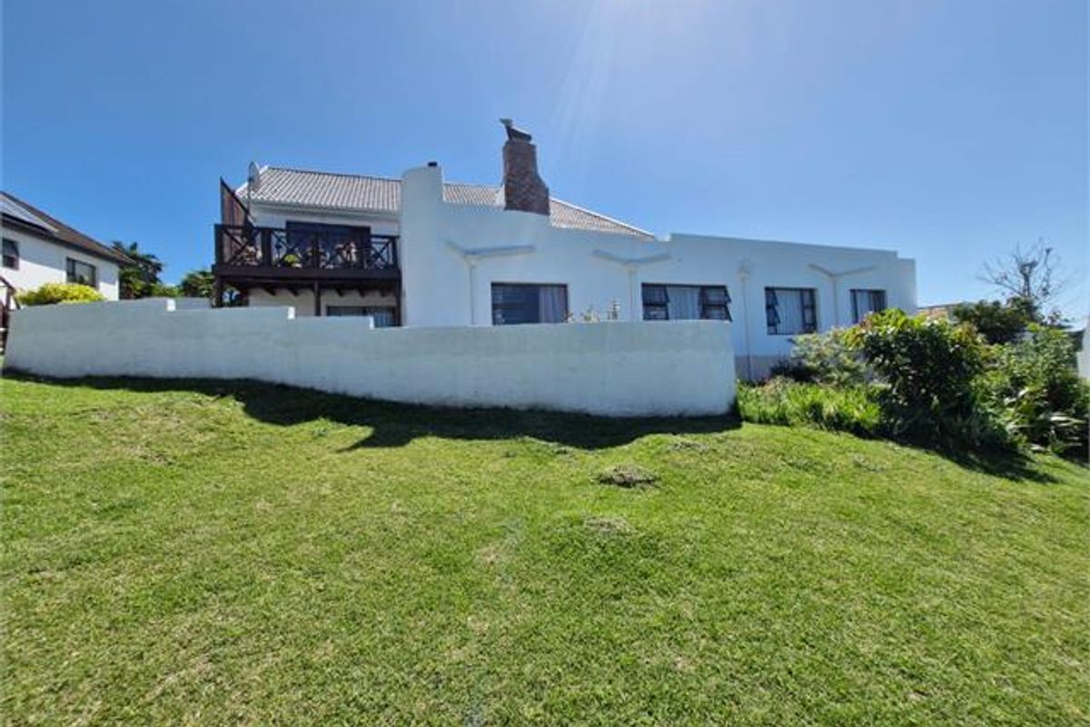 Rear view of the property featuring a white facade, brick chimney, and an elevated timber deck overlooking the garden.