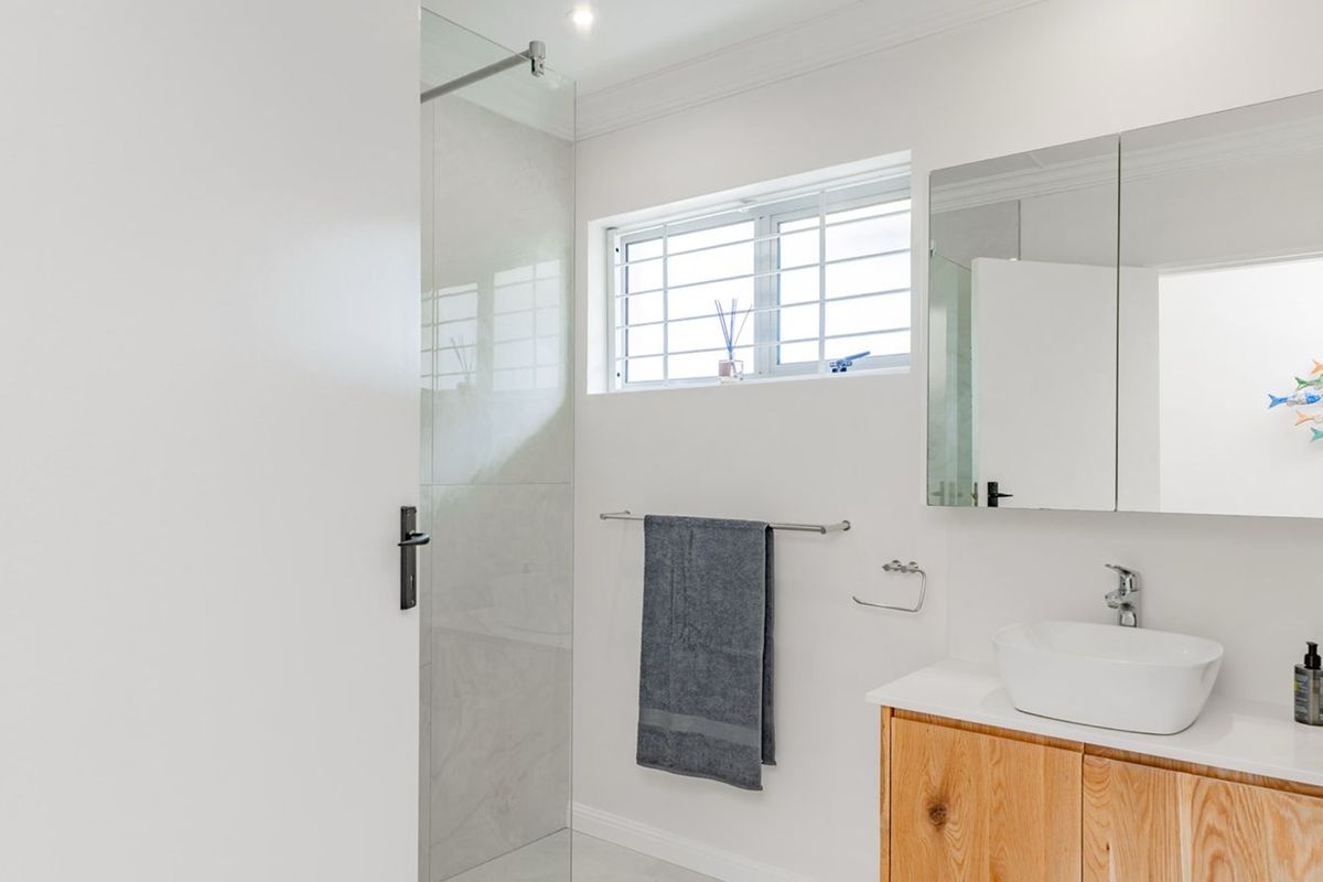Modern bathroom featuring a glass-enclosed shower, a wooden vanity with a vessel sink, and a mirrored medicine cabinet.