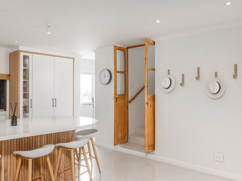 Modern open-plan kitchen featuring a central island with timber detailing, sleek white cabinetry, and a seamless transition to the staircase area.