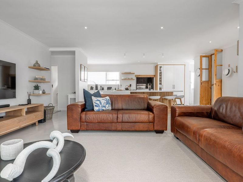 Spacious open-plan living area featuring a modern kitchen with a central island, recessed lighting, and neutral finishes throughout.