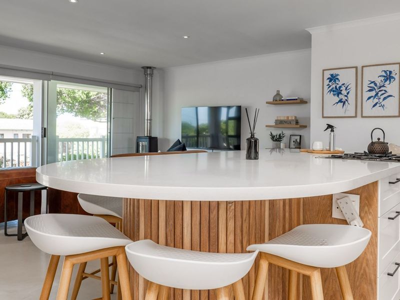Modern open-plan living area featuring a large kitchen island with stone countertop, integrated gas cooktop, and seamless flow to the outdoor patio area.