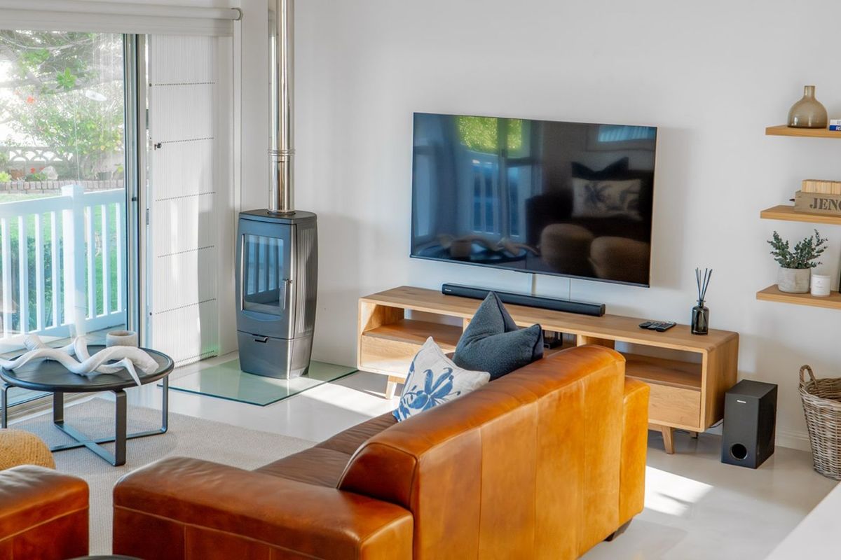 A bright living room featuring a modern freestanding fireplace, tiled flooring, and large sliding glass doors providing access to the outdoor patio area.