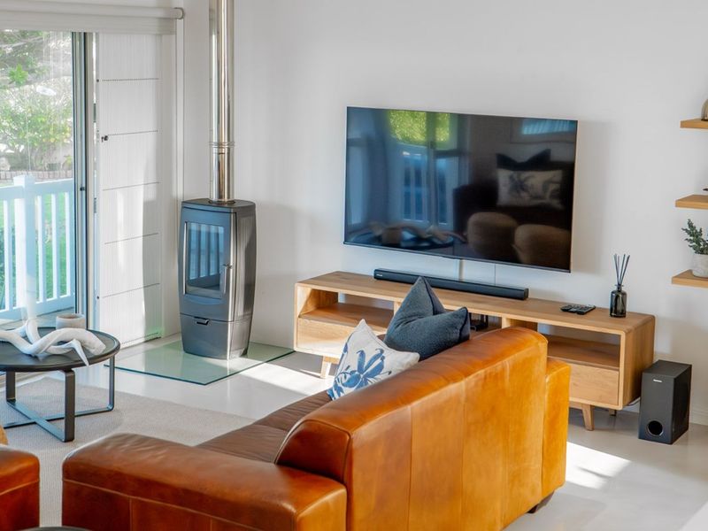 A bright living room featuring a modern freestanding fireplace, tiled flooring, and large sliding glass doors providing access to the outdoor patio area.