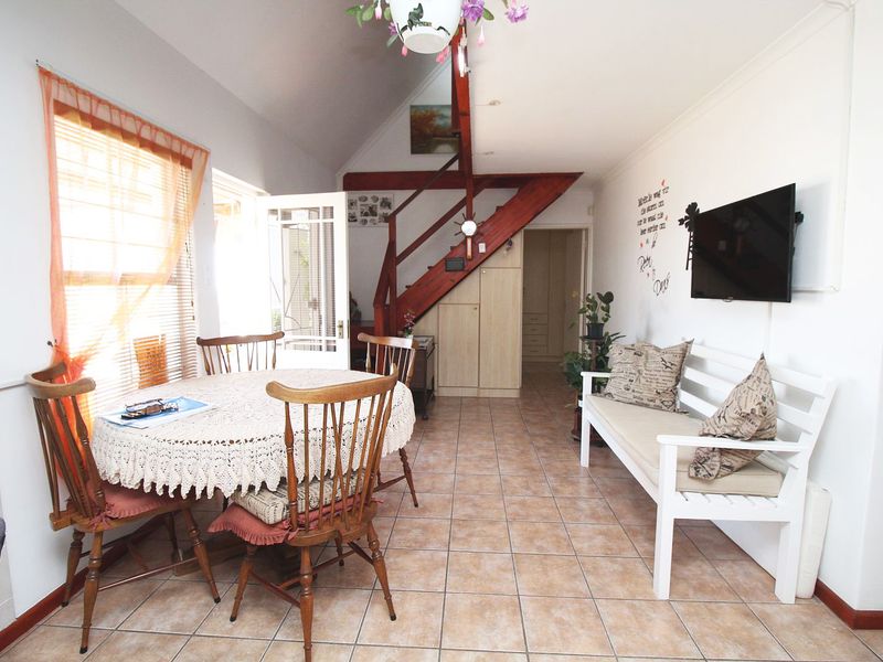 Open plan living and dining area featuring tiled flooring and a prominent wooden staircase leading to the upper level.