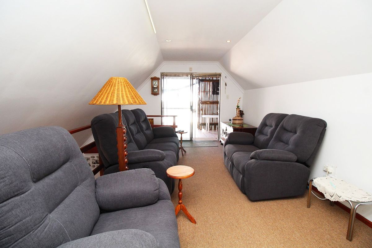 A cozy attic-style living room featuring sloped ceilings, carpeted flooring, and a sliding glass door providing access to an outdoor area.