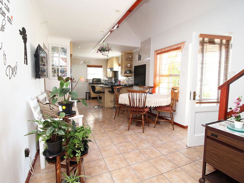 Open-plan living and kitchen area featuring tiled flooring, exposed ceiling beams, and a functional kitchen layout with an island.
