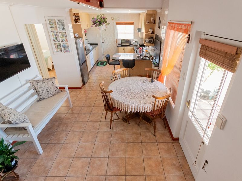 Open-plan living and kitchen area featuring tiled flooring, a breakfast bar, and direct access to the exterior through a glass panel door.