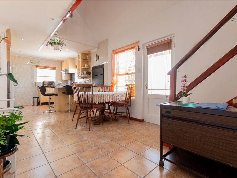 Open-plan living and kitchen area featuring tiled flooring, a vaulted ceiling, and a functional kitchen layout with an island and staircase access.