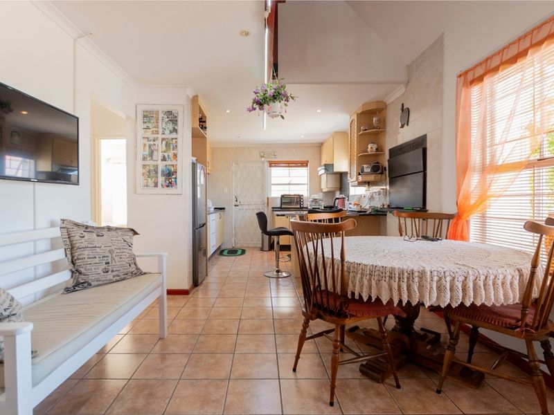 Open-plan living and kitchen area featuring tiled flooring, built-in cabinetry, and a bright, functional layout suitable for modern updates.