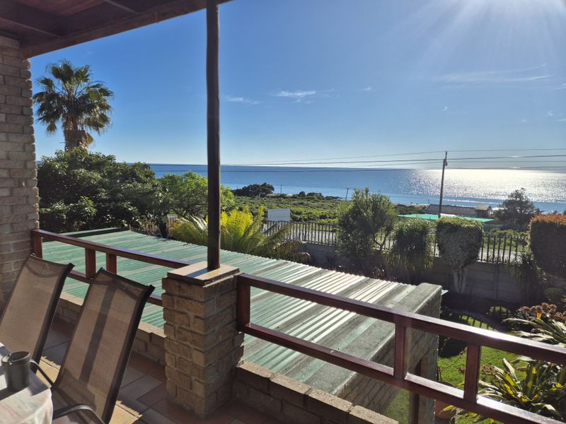 Covered patio area featuring brick pillars and timber railings, offering an elevated view of the surrounding landscape and ocean.
