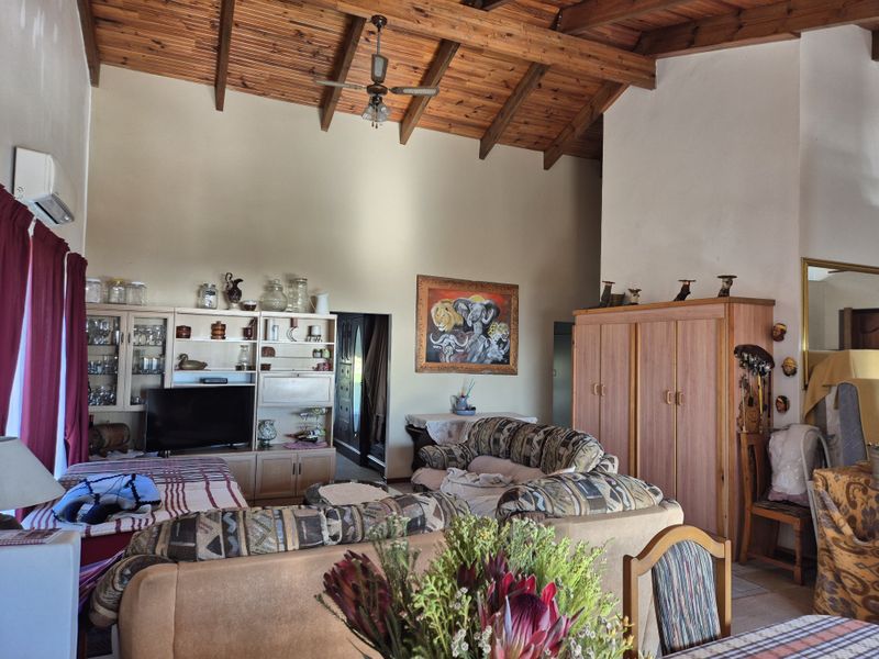 Spacious living room featuring a high vaulted ceiling with exposed timber beams and built-in cabinetry, offering a warm and traditional aesthetic.
