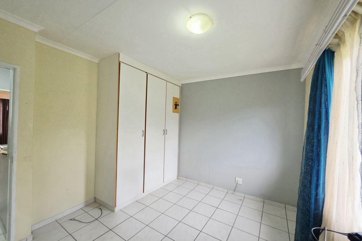 A vacant bedroom featuring built-in cupboards, tiled flooring, and neutral wall finishes, offering a clean canvas for personalization.