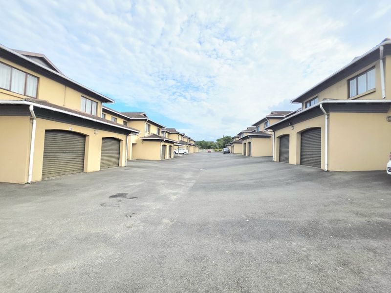 A view of the townhouse complex driveway featuring multiple garage entrances and uniform building facades.