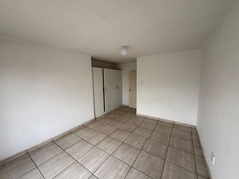 An empty bedroom featuring neutral tiled flooring and built-in storage cupboards, offering a blank canvas for personalization.