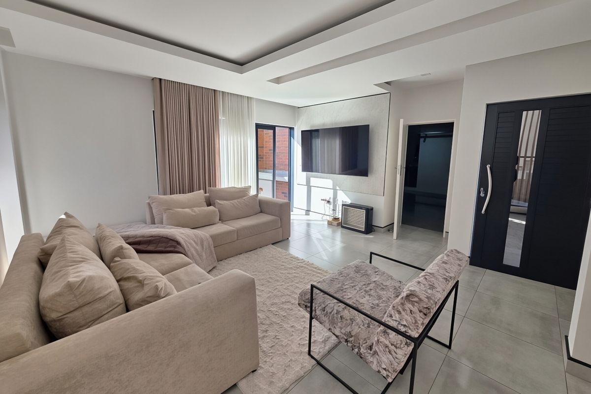 Modern living room featuring tiled flooring, a recessed ceiling design, and a sliding glass door providing natural light.