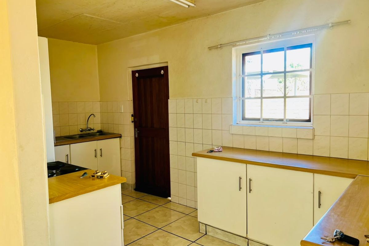 A dated kitchen featuring built-in cabinetry, laminate countertops, tiled backsplash, and tiled flooring, offering a functional layout ready for modernization.