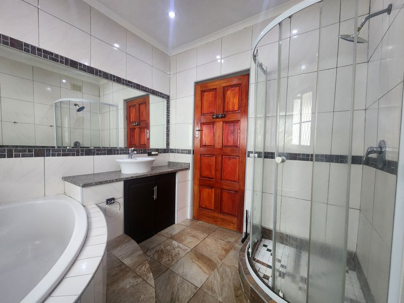 A well-maintained bathroom featuring a corner shower, built-in bathtub, vanity with vessel sink, and tiled finishes throughout.