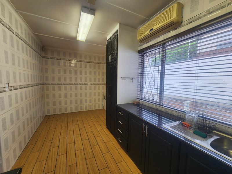 A functional kitchen featuring dark cabinetry, granite countertops, stainless steel sink, and tiled walls, offering a clean and practical workspace.