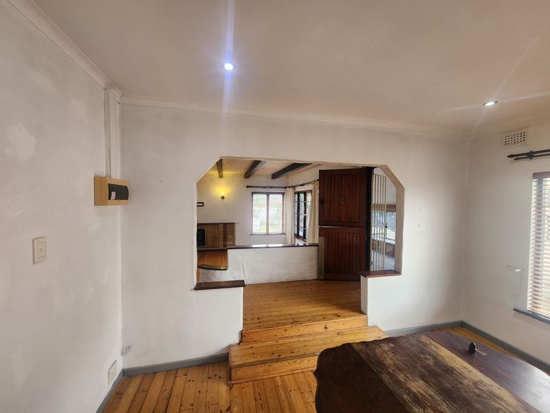 Spacious living area featuring original timber flooring, raised floor transition, and characterful architectural openings connecting to adjacent living spaces.