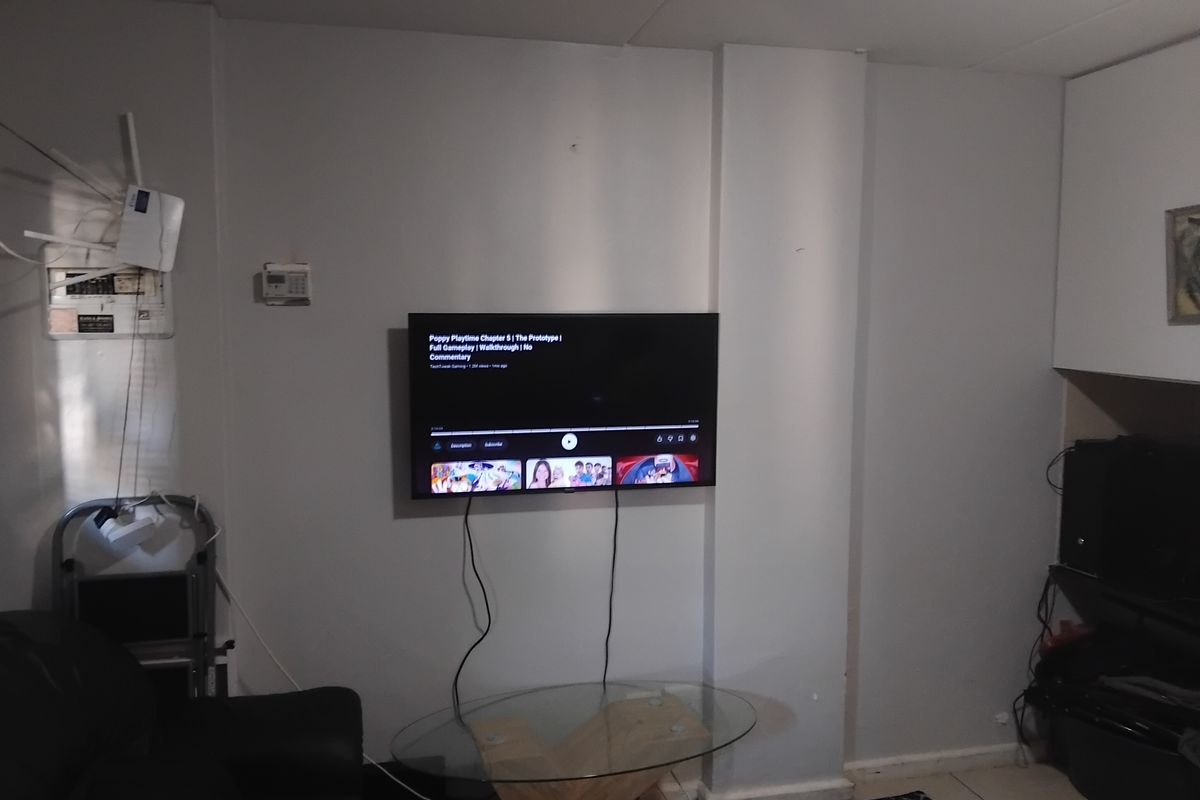 A living room area featuring tiled flooring and built-in cabinetry, currently showing signs of wear and exposed wiring.