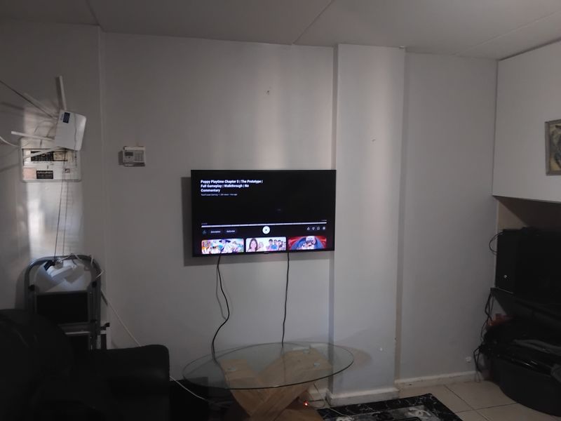 A living room area featuring tiled flooring and built-in cabinetry, currently showing signs of wear and exposed wiring.