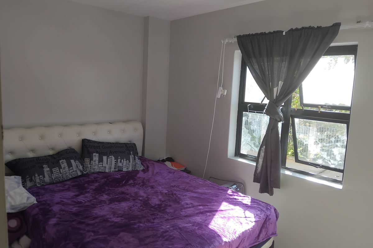 A bedroom featuring neutral wall paint and an aluminium-framed window with natural light.