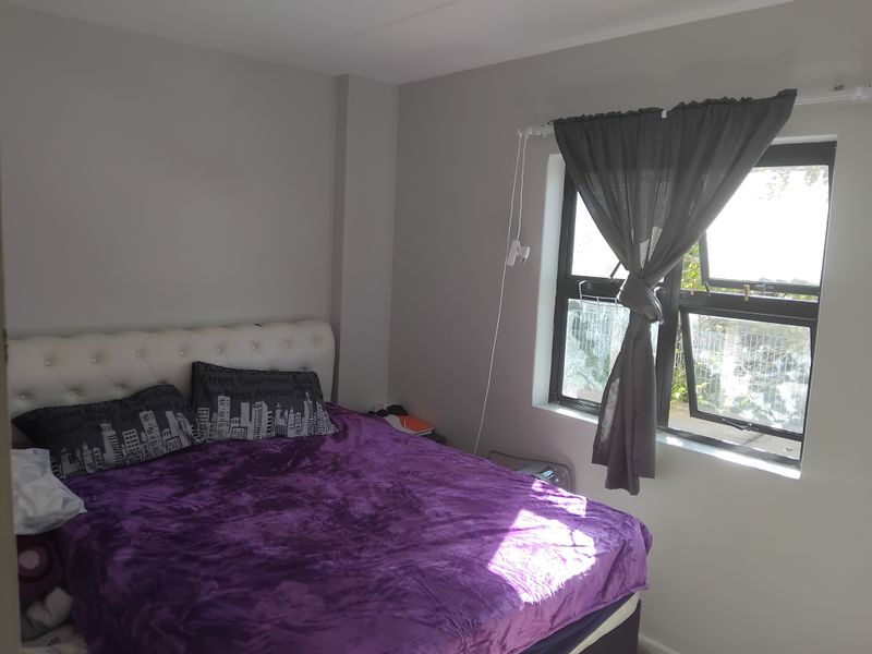 A bedroom featuring neutral wall paint and an aluminium-framed window with natural light.