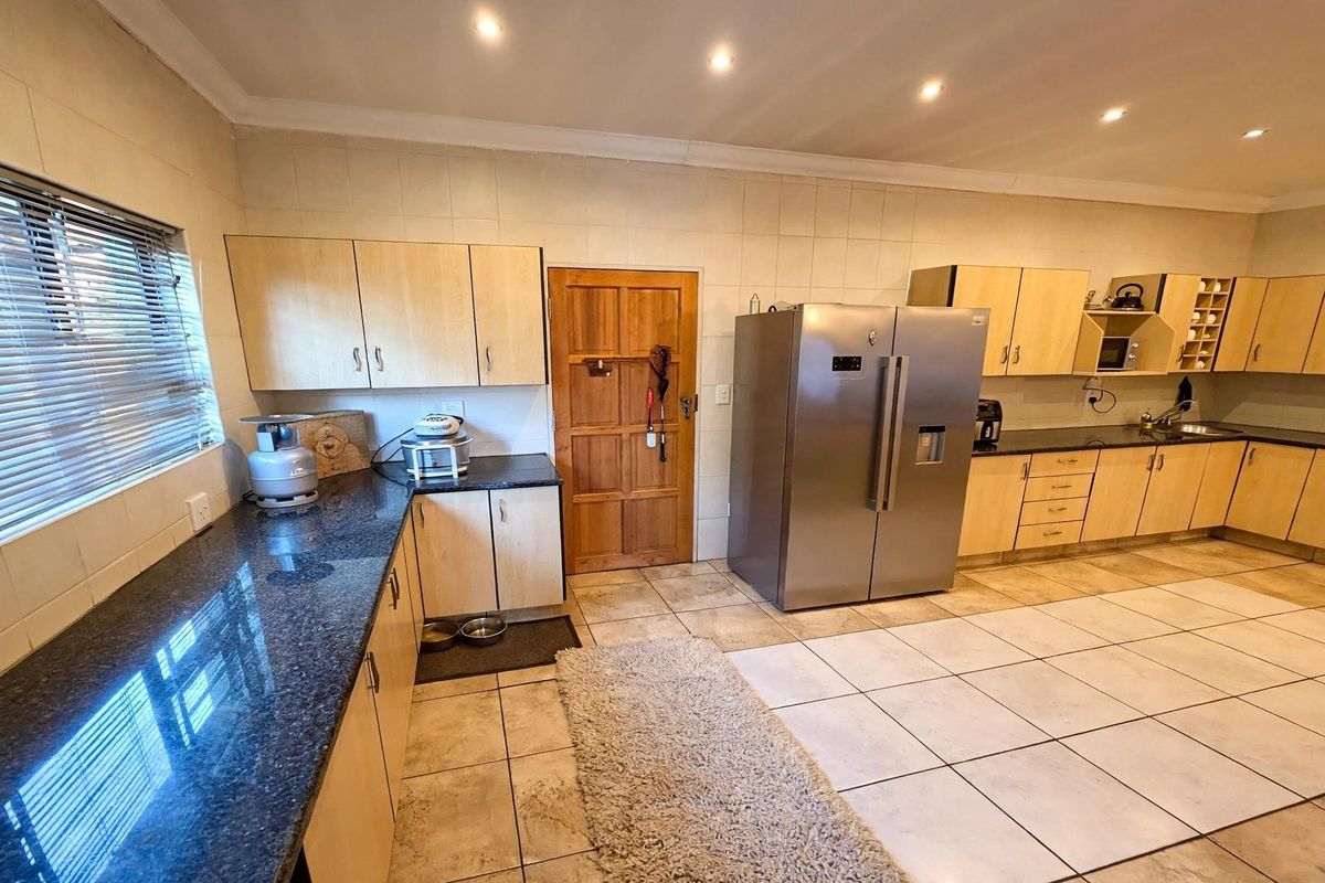 Spacious kitchen featuring light wood cabinetry, dark granite countertops, tiled flooring, and recessed lighting, offering a functional layout with ample storage space.