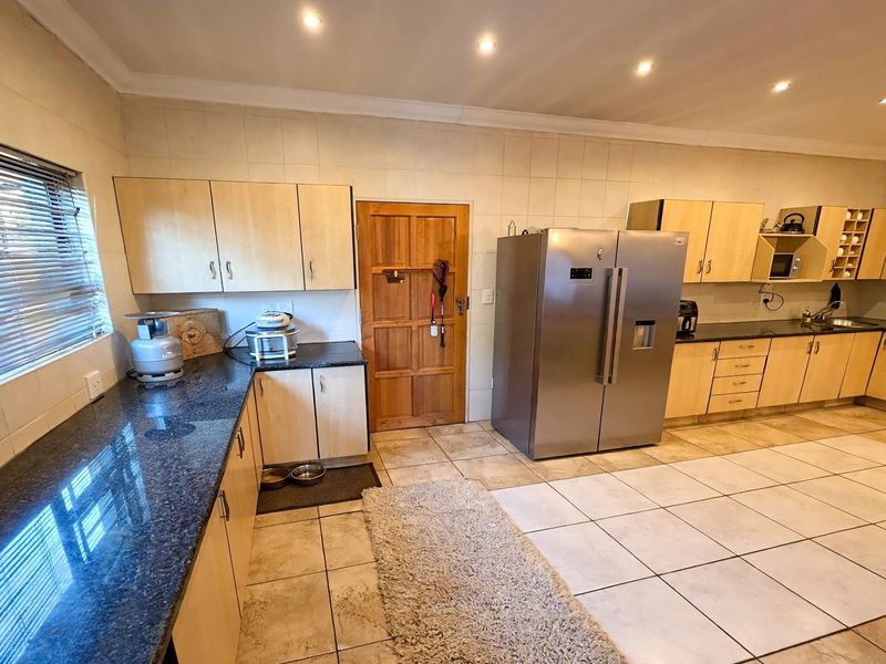 Spacious kitchen featuring light wood cabinetry, dark granite countertops, tiled flooring, and recessed lighting, offering a functional layout with ample storage space.