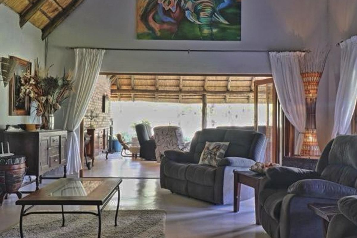 Spacious living room featuring a high thatched ceiling with exposed rafters and large sliding doors opening onto a covered patio area.