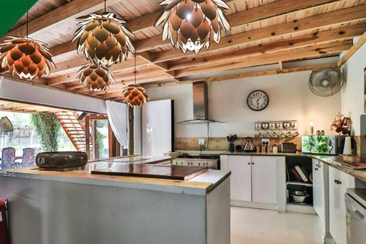 A rustic-style kitchen featuring exposed timber ceiling beams, a central island, and direct access to an outdoor area through large sliding glass doors.