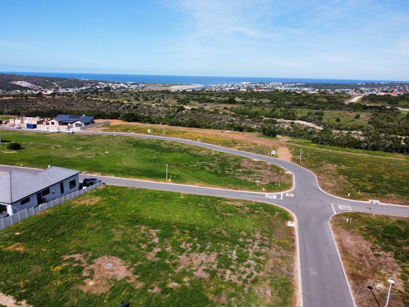 Aerial view of a residential development site featuring paved roads, street lighting, and expansive coastal views.
