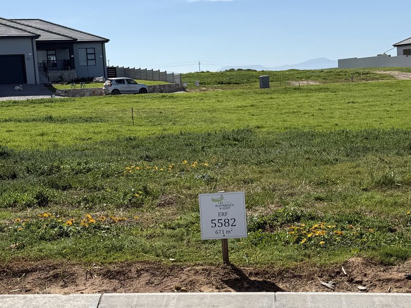 A vacant residential plot of 671 square meters, situated in a developed estate with surrounding homes and clear boundary markers.